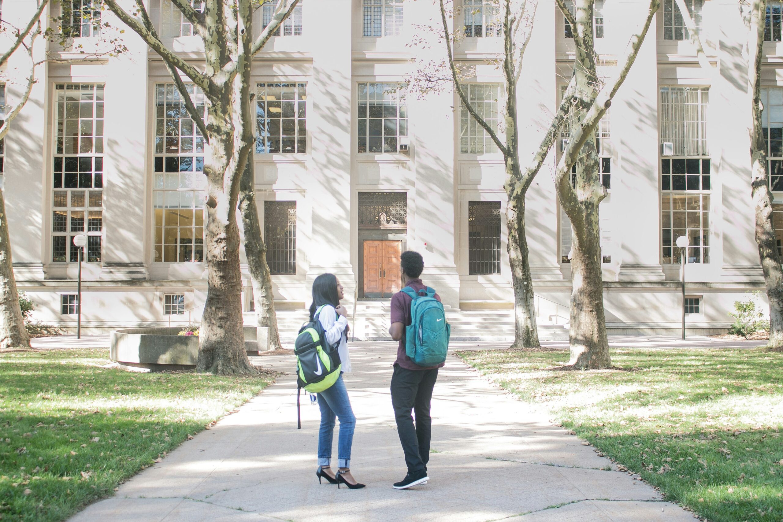 Students standing in front of a school with backpacks on