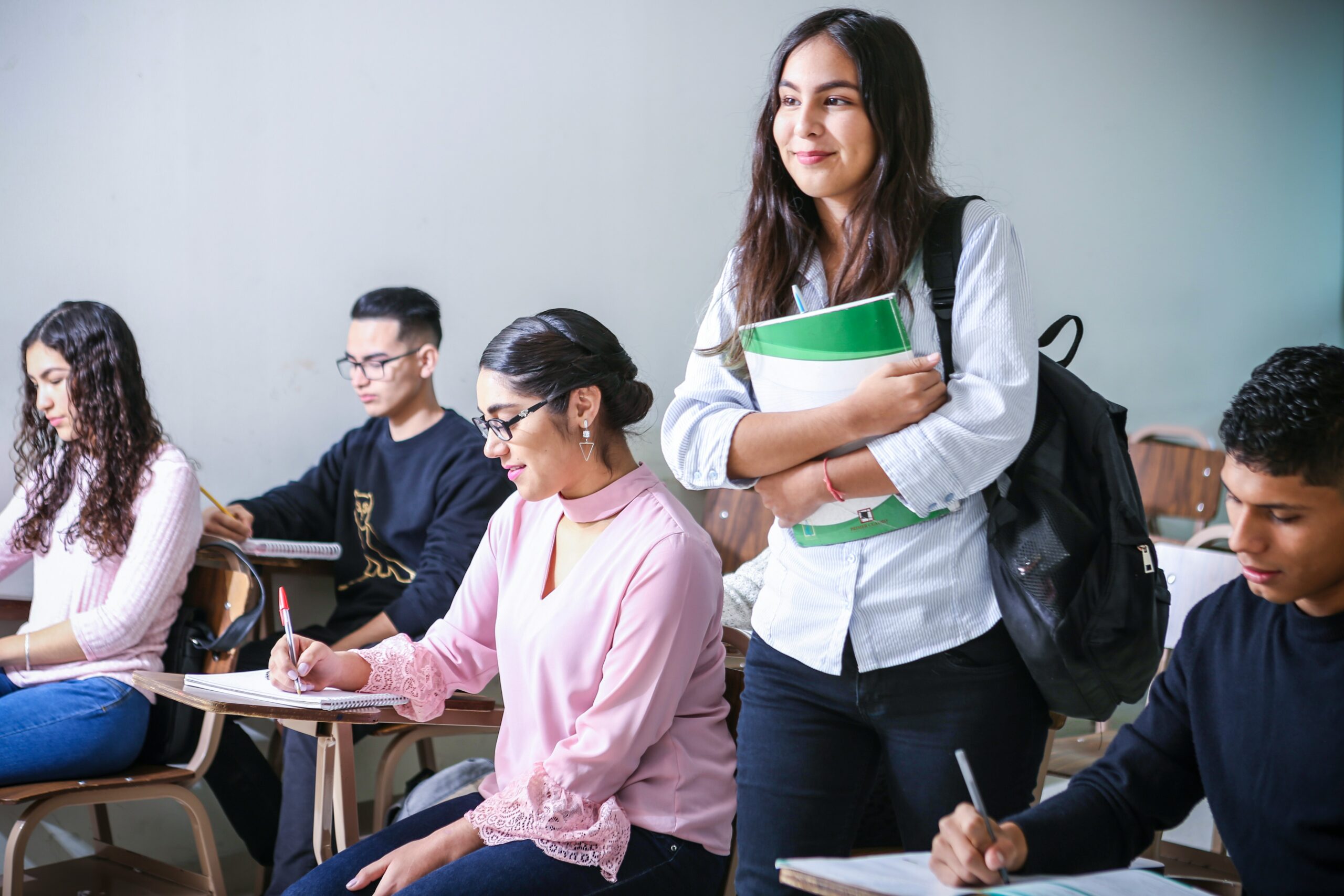 Student standing up and smiling in a classroom while holding books